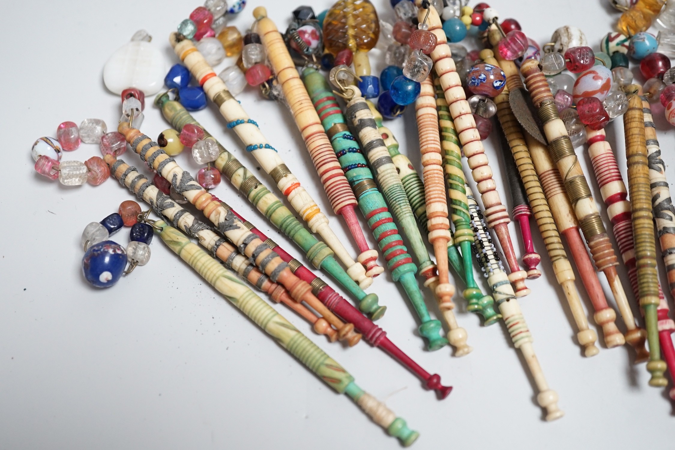 Twenty one 19th century stained and turned bone lace bobbins with glass bead tops and thirteen ornate bone and metal decorated lace bobbins with bead tops (35)